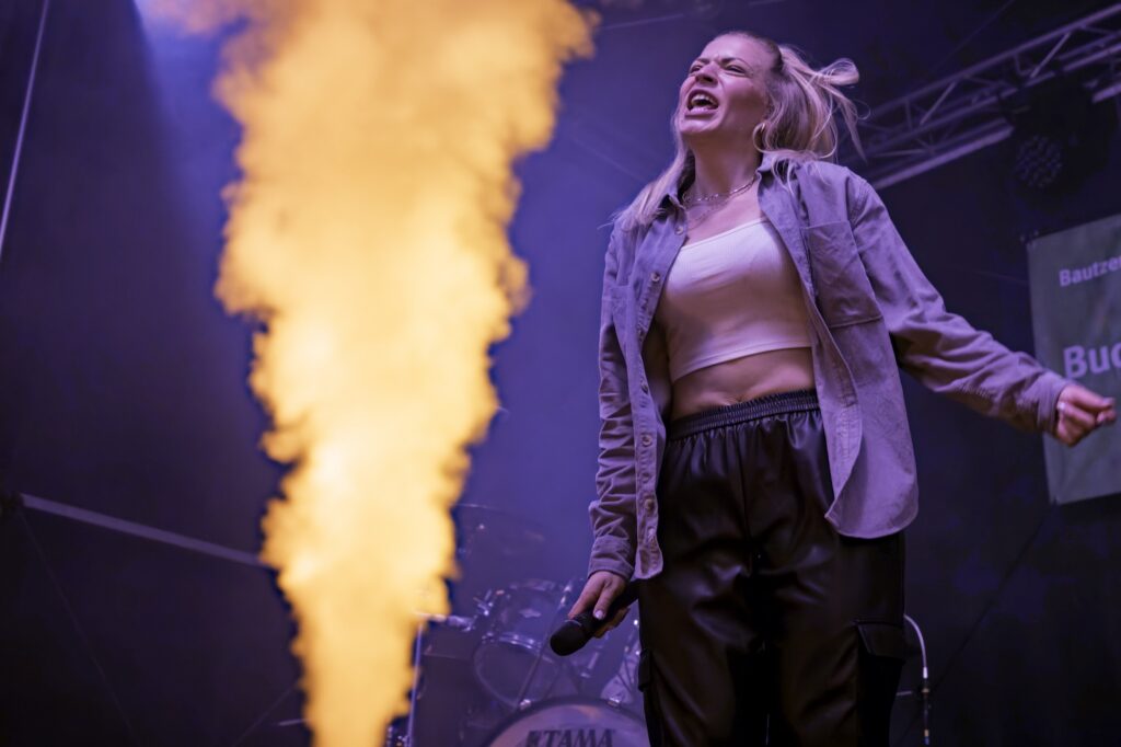 Sängerin der HOUSE PLAYER neben einer angestrahlten Nebelfontäne während der Bühnenshow