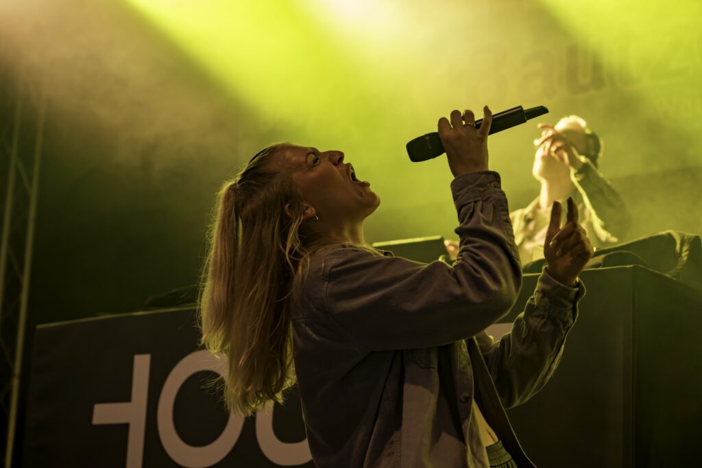 Sängerin der HOUSE PLAYER performt live auf der Bühne im gelben Scheinwerferlicht