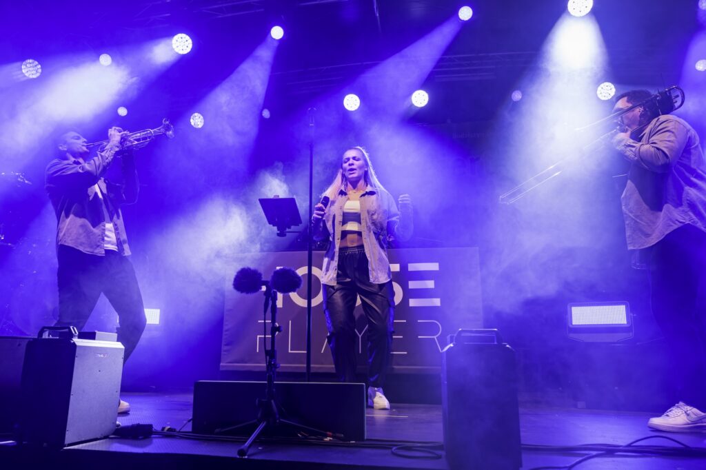 Trompeter und Sängerin der HOUSE PLAYER bei ihrer Bühnenshow im blauen Licht